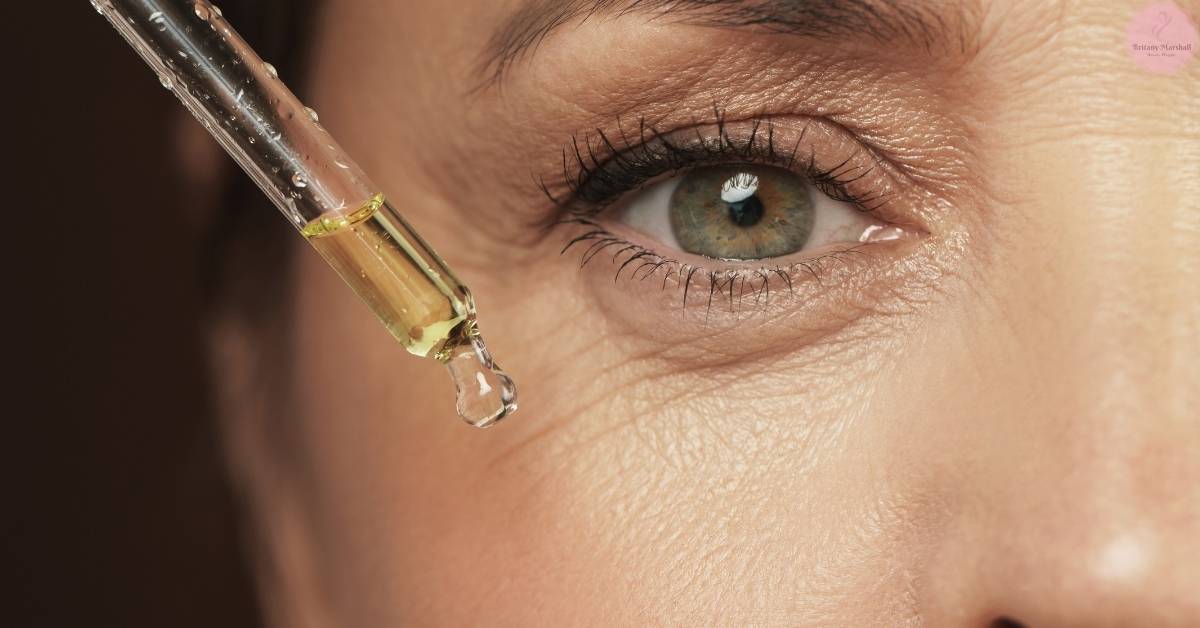 a close-up of an eye receiving a drop of advanced eyelash serum from a dropper