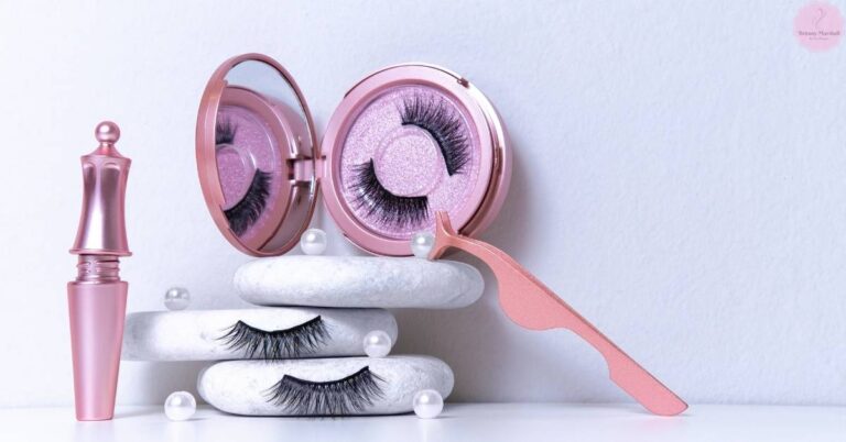 a pink eyelash serum bottle, applicator brush, and false lash cases with curled lashes on textured stones