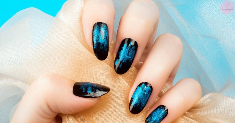a hand showcasing stylish almond-shaped nails with deep black and shimmering blue ombré nail polish, accented with gold tips