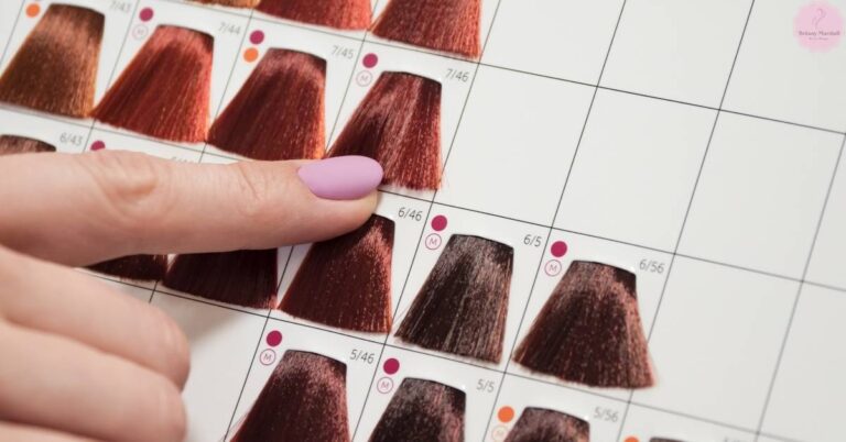 a hand selecting a hair color swatch from a professional hair coloring guide chart showing various shades of brown and black hair tones.