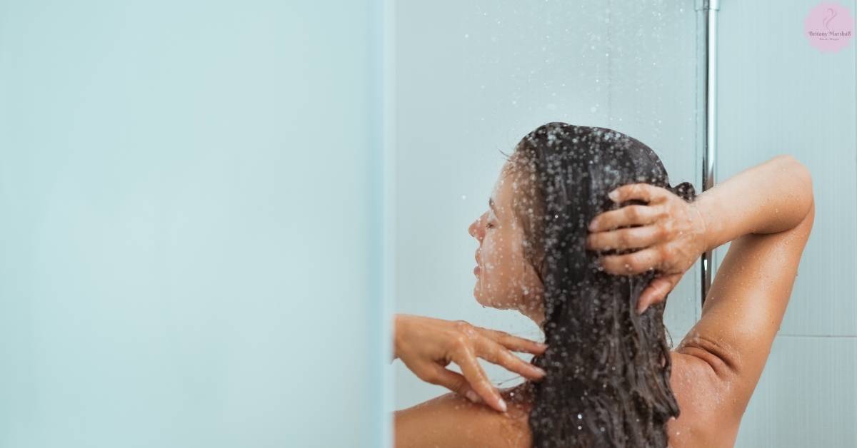 a person washing their wet hair under a shower stream, ensuring hair is thoroughly rinsed