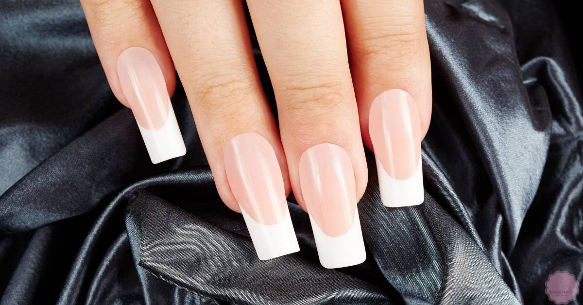 a hand displaying neatly applied press-on nails in various stylish shapes and sizes, showcasing a clean, salon-quality finish.
