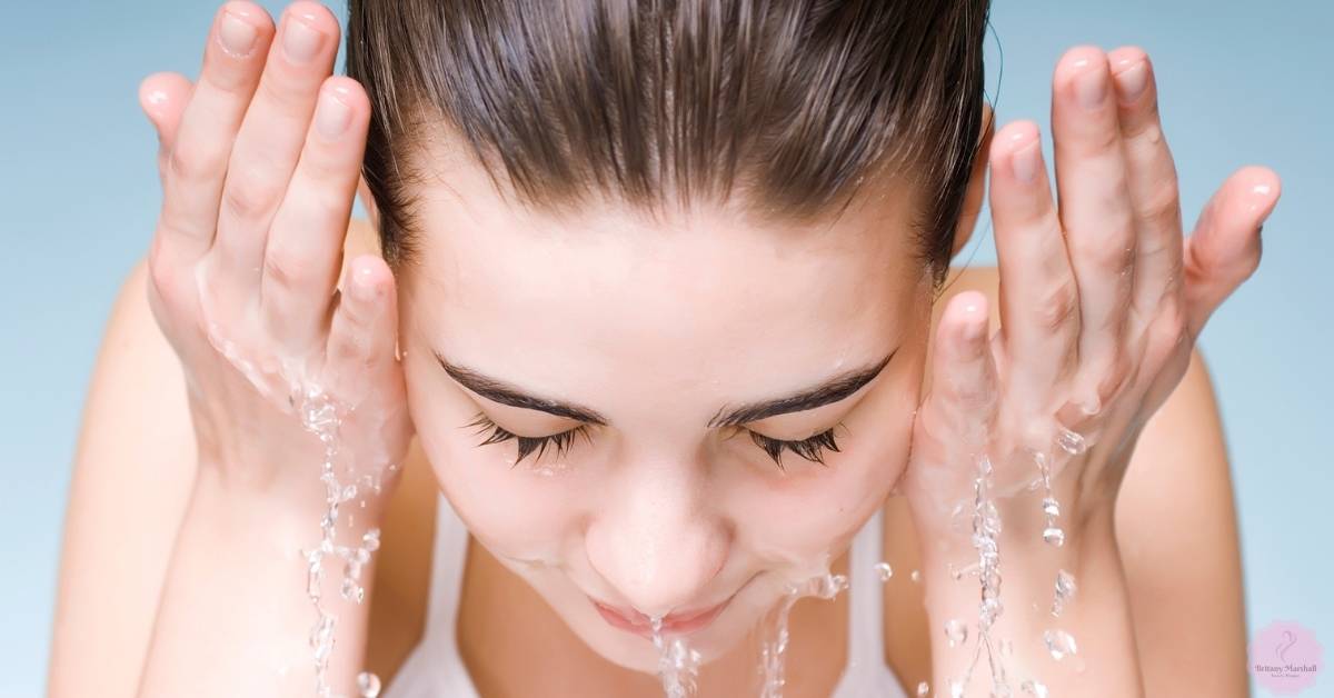 a person gently washing their face with water streams, emphasizing careful eyebrow area cleaning for proper microblading aftercare