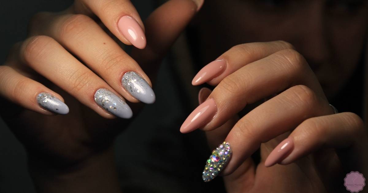 a close-up of elegant winter nail art featuring glittery silver and iridescent rhinestone accents on long, almond-shaped nails
