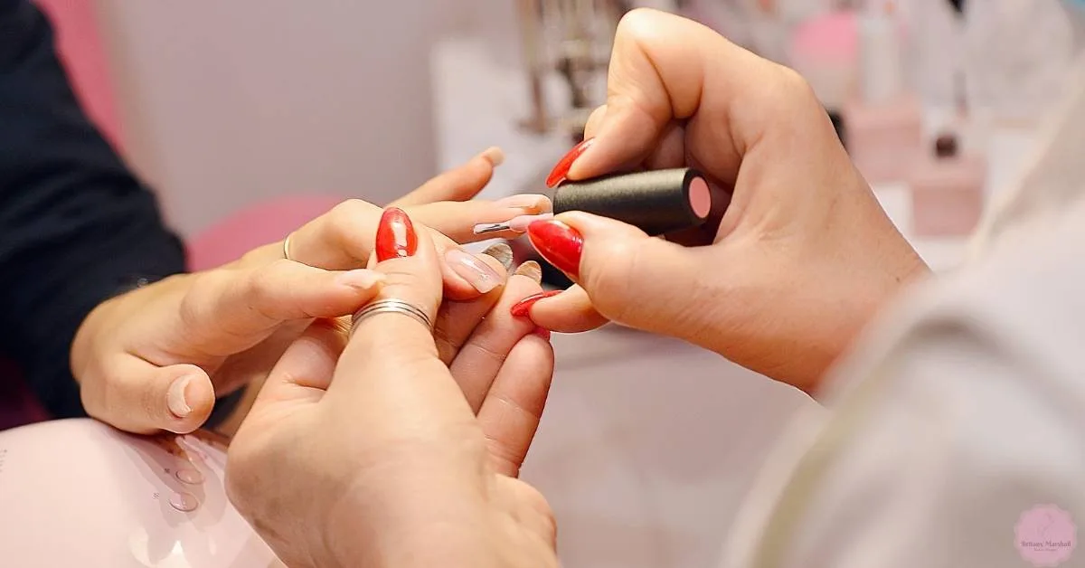 a pair of hands gently massaging nails with pink-tipped fingers, showcasing well-maintained nail care.