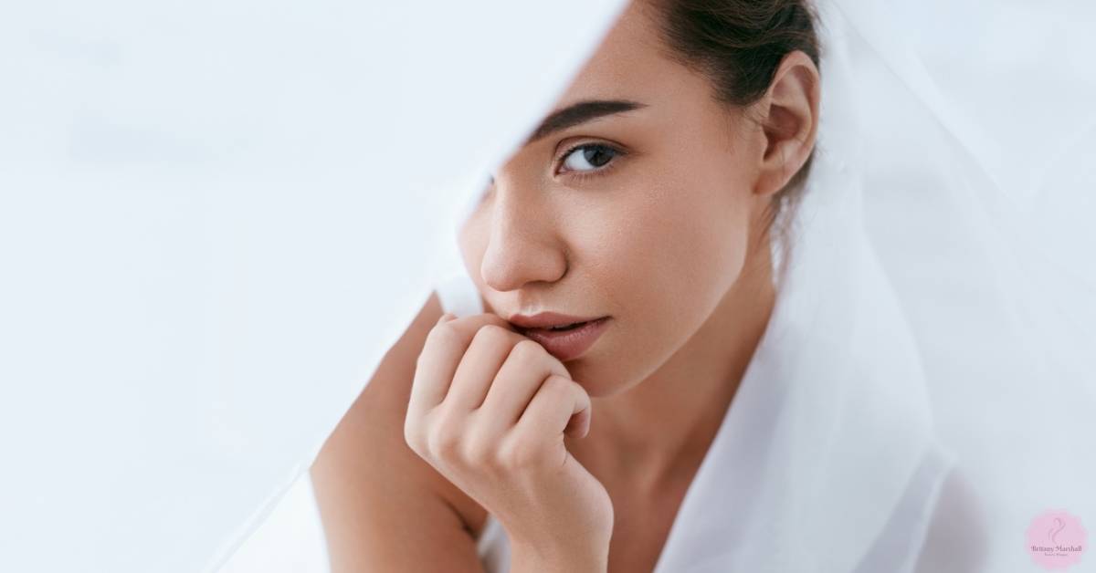 a woman gently touching her chin, showcasing clear skin and natural beauty.