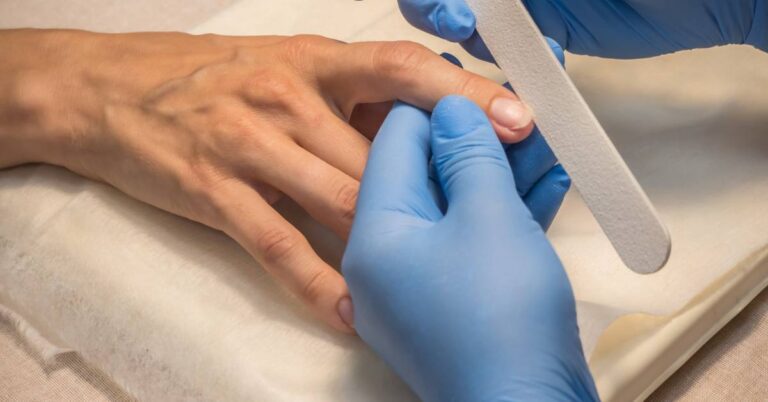 a gloved hand demonstrating nail curvature by pressing on a person’s flat nail plate to show natural nail bed flexibility
