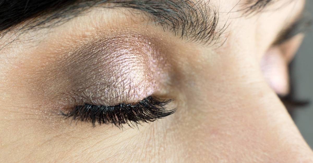 a closed eye with droopy eyelashes showing signs of heavy mascara application.