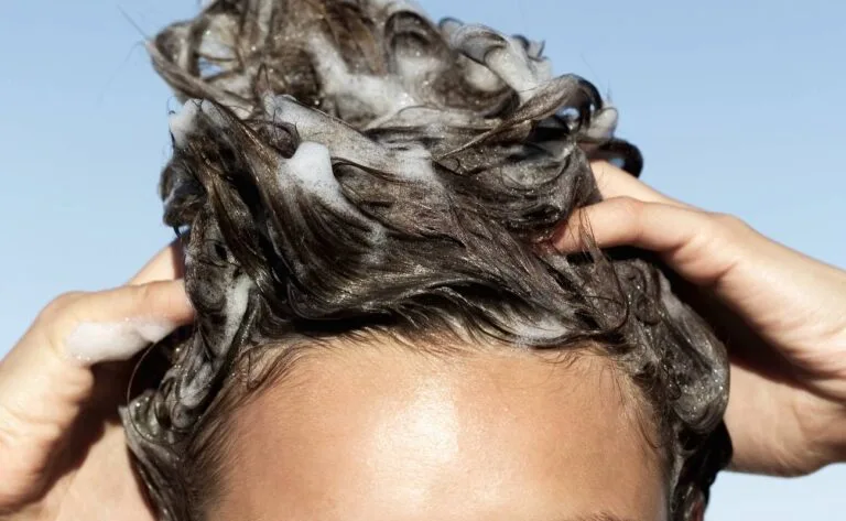 a person applying shampoo to wet hair for potential toxin removal during a hair detox process