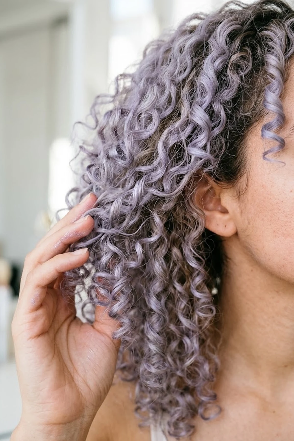 Close-up beauty portrait of bouncy spiral curls tinted with soft lavender haze temporary hair makeup gel in bright studio lighting (AI Generated Image)