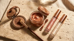 Editorial horizontal beauty showcase of temporary hair makeup ideas featuring metallic copper curl color wax, mineral root touch-up powder on a sleek bun hairline, and holographic shimmer gel streaks in warm studio sunlight
