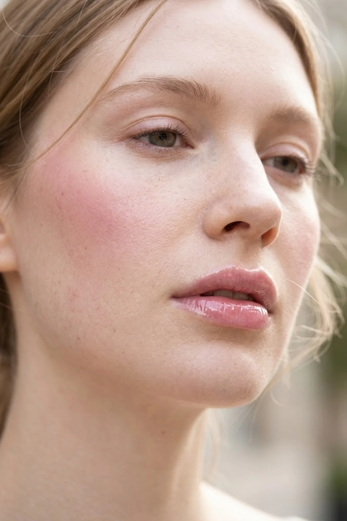 20 Effortless Natural Makeup Looks for an Everyday 'No-Makeup' Glow (2026 Inspo) 27 Close-up beauty portrait of fair porcelain skin wearing translucent cool-rose cream blush and high-shine hyaluronic acid lip oil in soft diffused daylight (AI Generated Image)